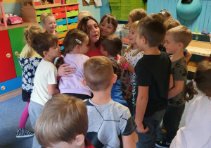 Dzieci przytulają panią dyrektor w podziękowaniu za przeczytaną bajkę.